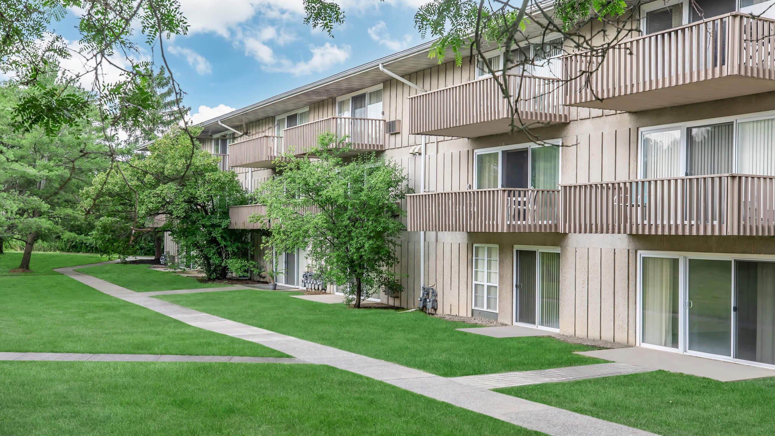 Apartment community surrounded by mature trees and a large green lawn