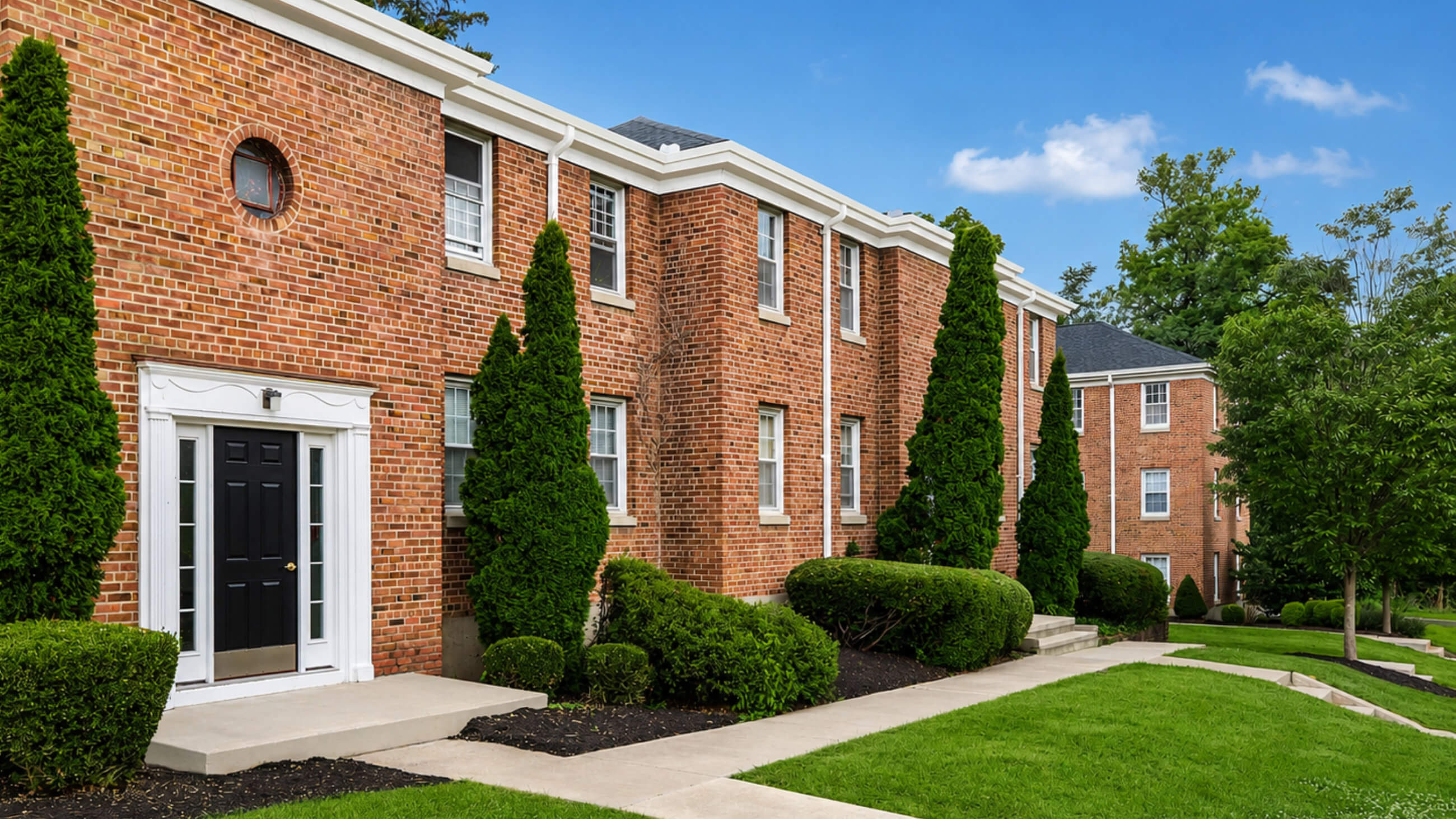 Brick apartment building with manicured landscaping and walkway