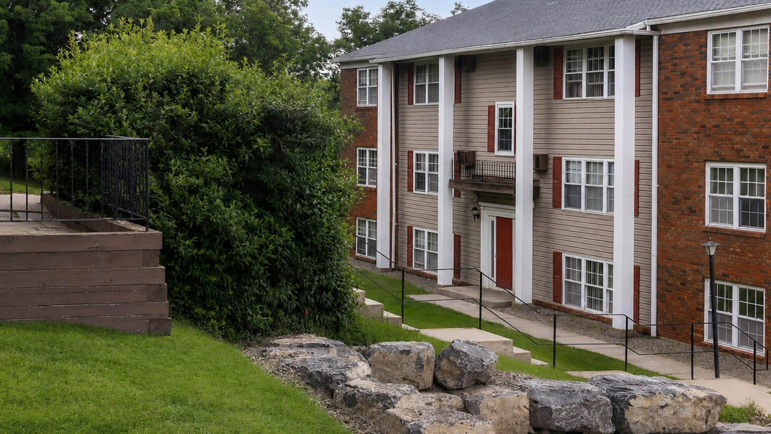 Apartment buildings on a landscaped hillside with stone retaining wall